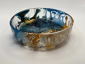Decorative resin bowl with blue, white, and gold colors on a light gray background