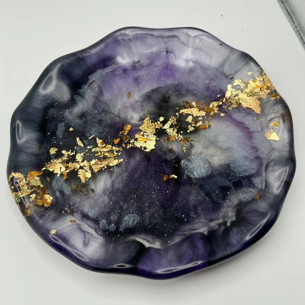 Decorative plate with purple and black marbled design and gold flakes on a white background