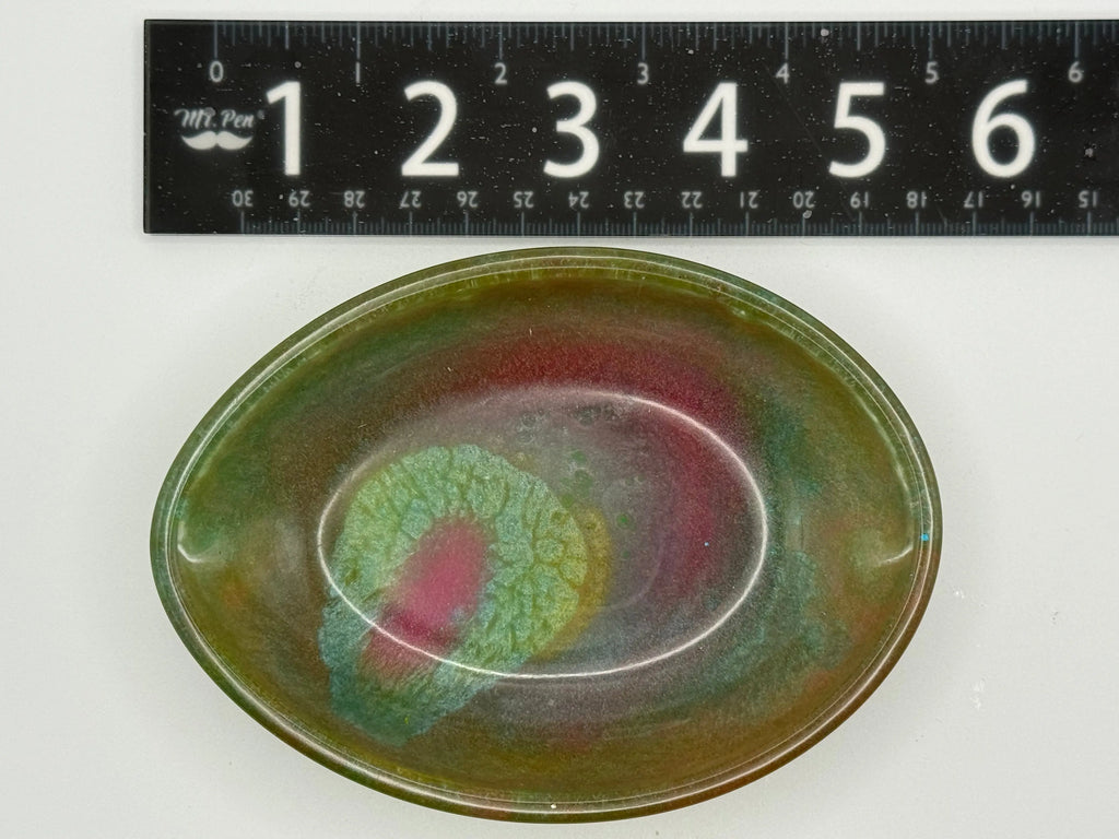 Artistic resin soap dish or trinket tray with multicolored glaze on a white background, with a ruler for scale.