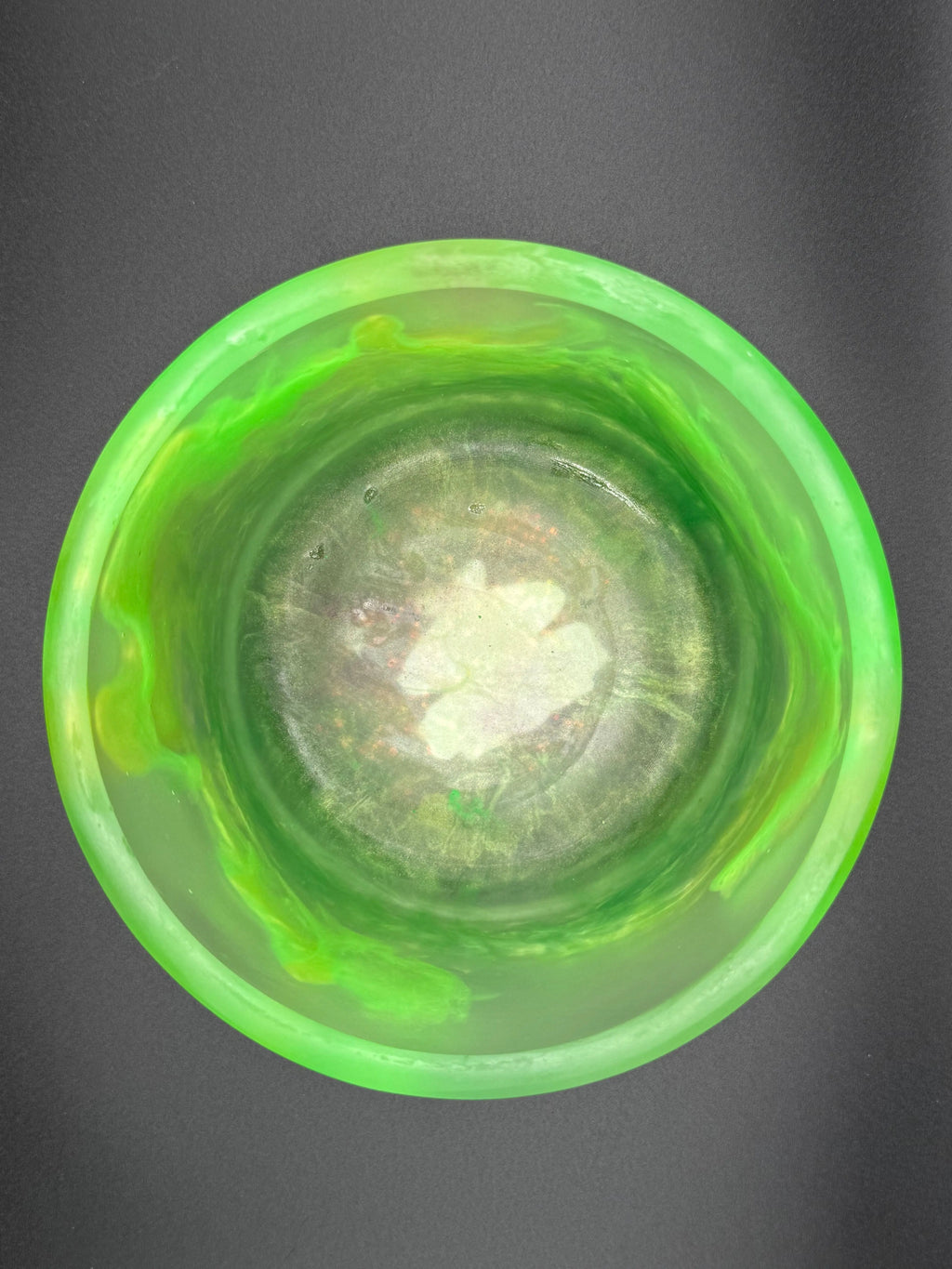 Green glass bowl with a textured interior on a dark background