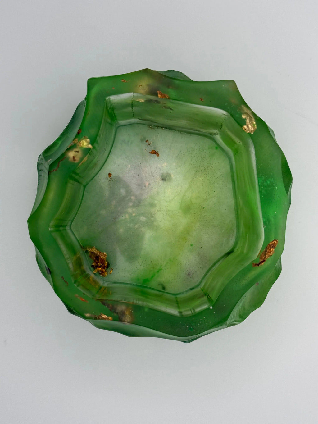 Green resin bowl with gold and copper leaf on a white background