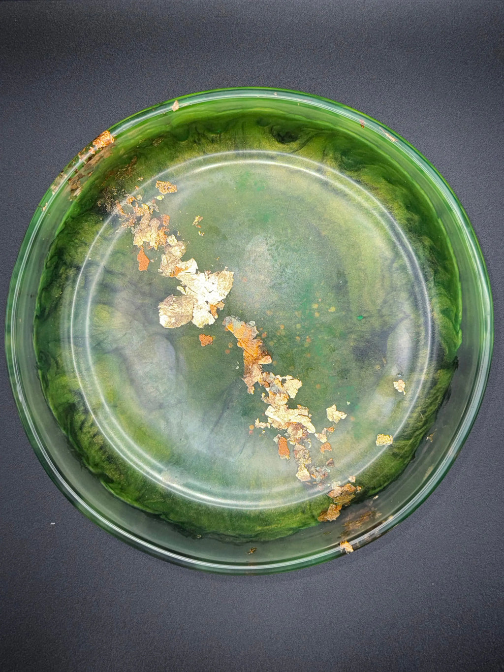 Green and black glass resin bowl with gold leaf on a dark background