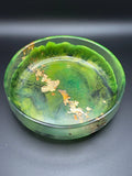Green and black glass resin bowl with gold leaf on a dark background