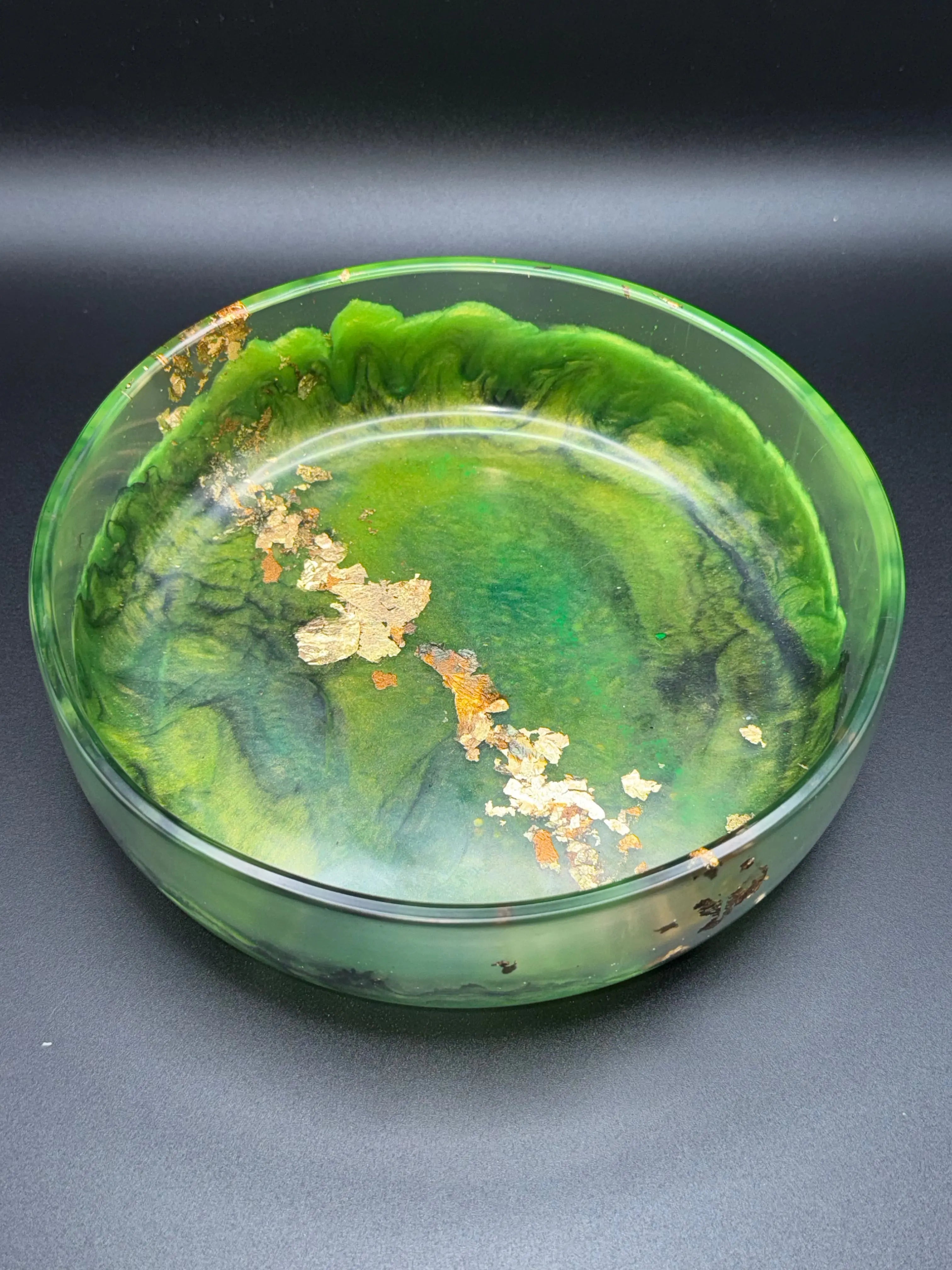 Green and black glass resin bowl with gold leaf on a dark background