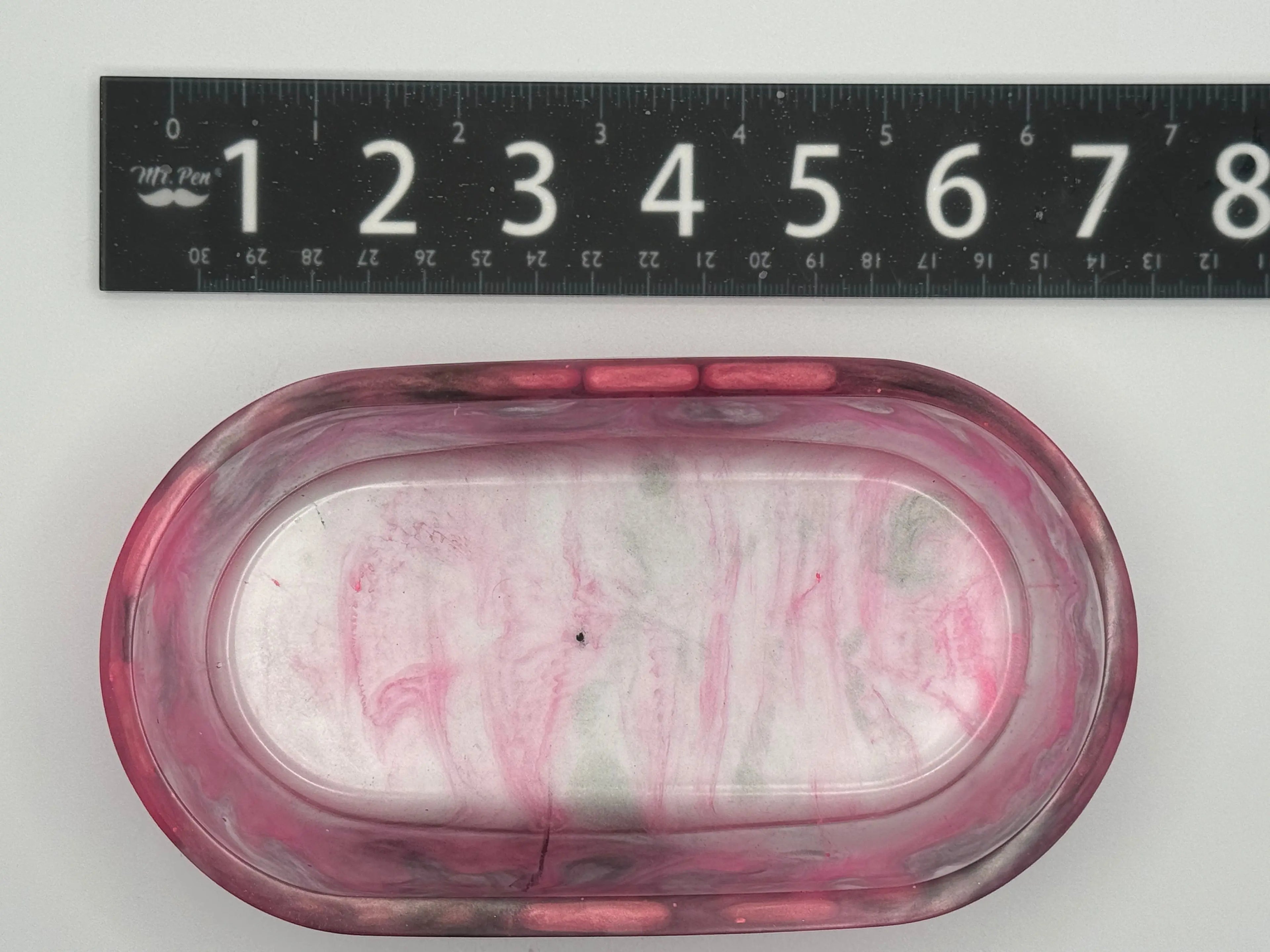 Marbled pink and gray resin with ruler for scale on a white background