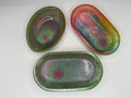 Three oval soap dishes or trinket trays with multicolored colors on a white background. 