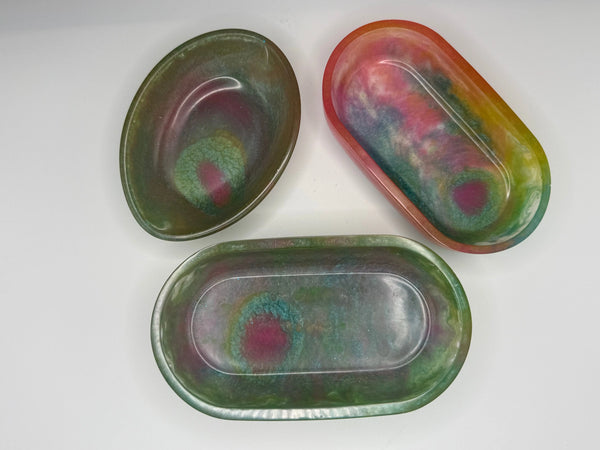 Three oval soap dishes or trinket trays with multicolored colors on a white background. 