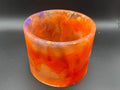 Decorative resin vase with orange and purple marbled pattern on a dark background