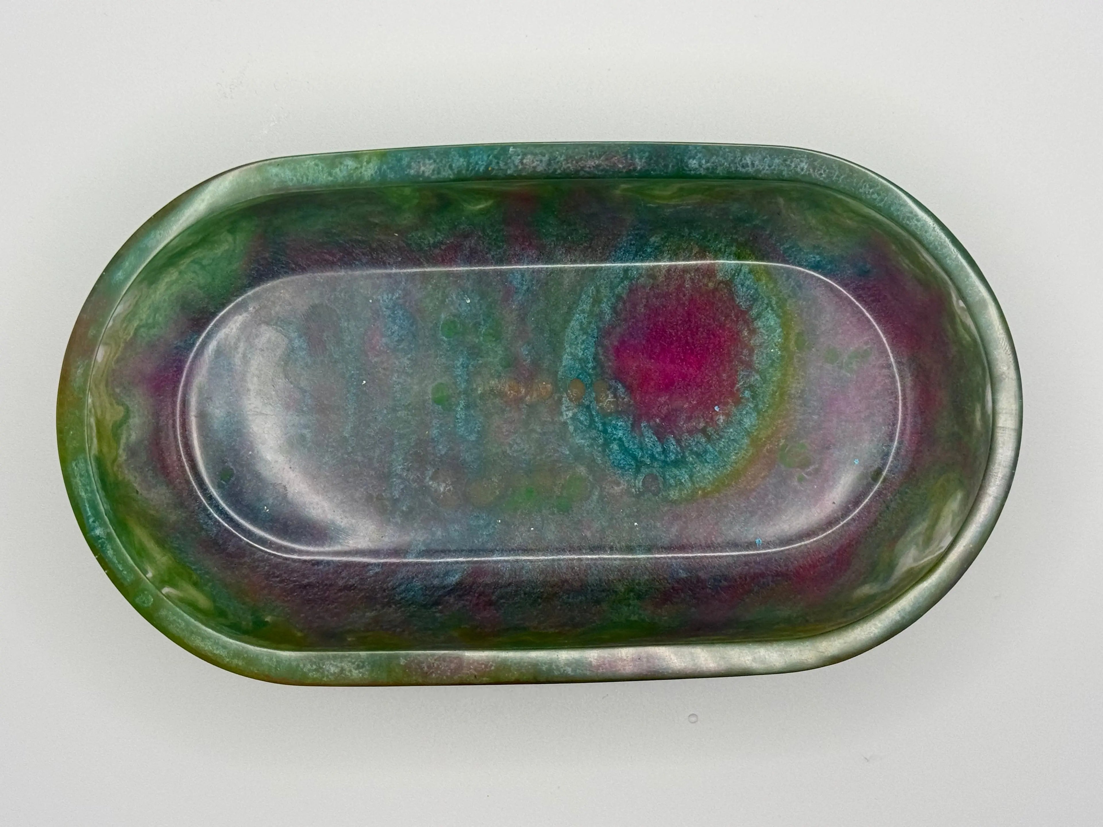 Oval resin dish in multicolors with green, blues and pinks on white background