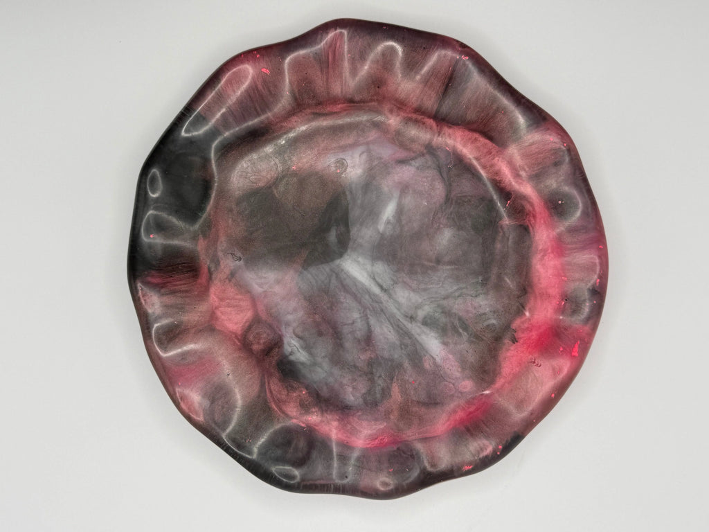 Decorative plate with a florescent pink and black abstract design on a white background