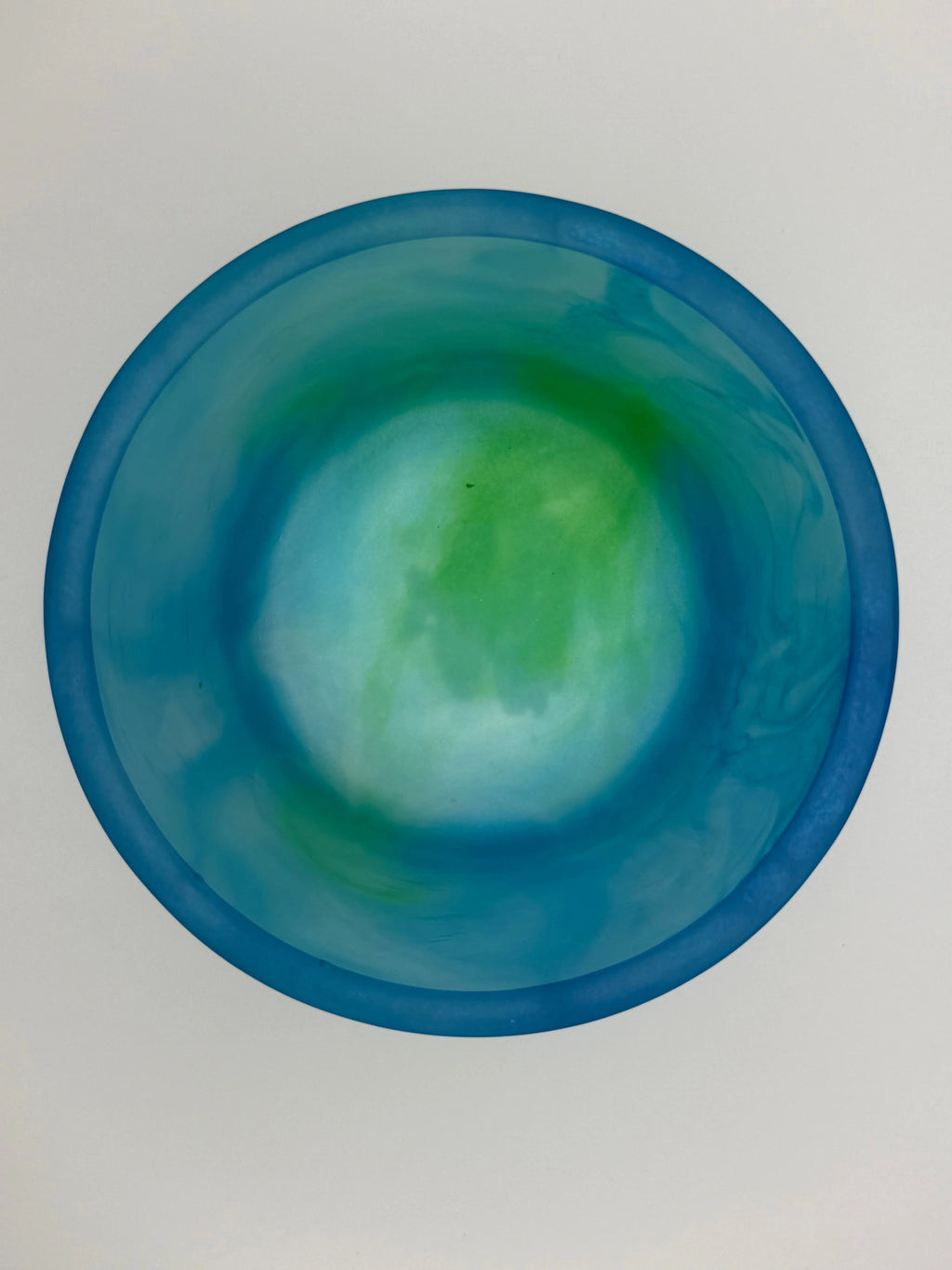 Blue resin planter cup with green tint on a light gray background