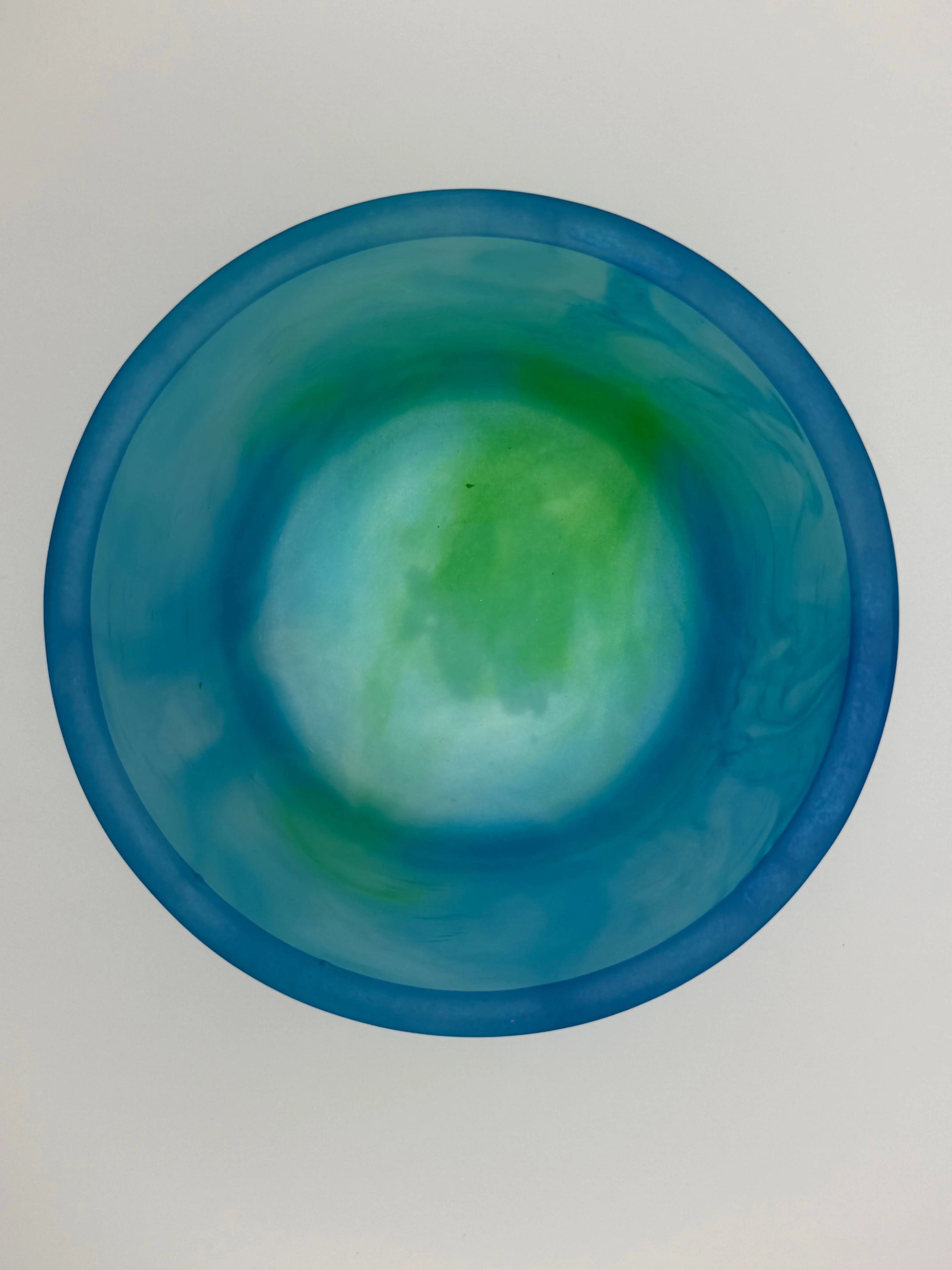 Blue resin planter cup with green tint on a light gray background